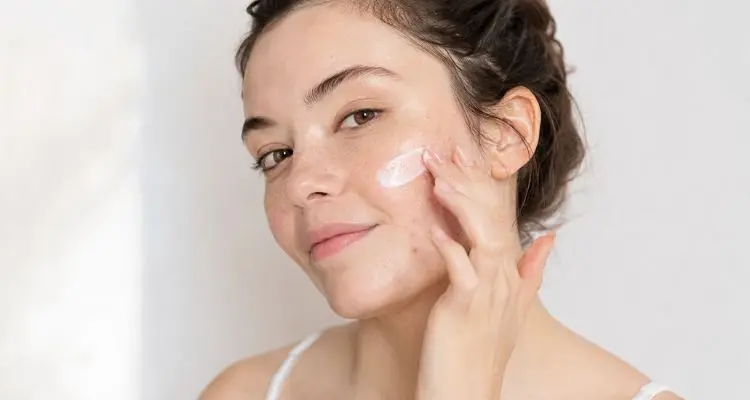 Woman applying non-comedogenic sunscreen on acne-prone skin